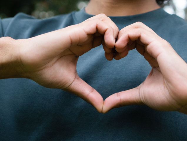 A person holding their hands in the shape of a heart