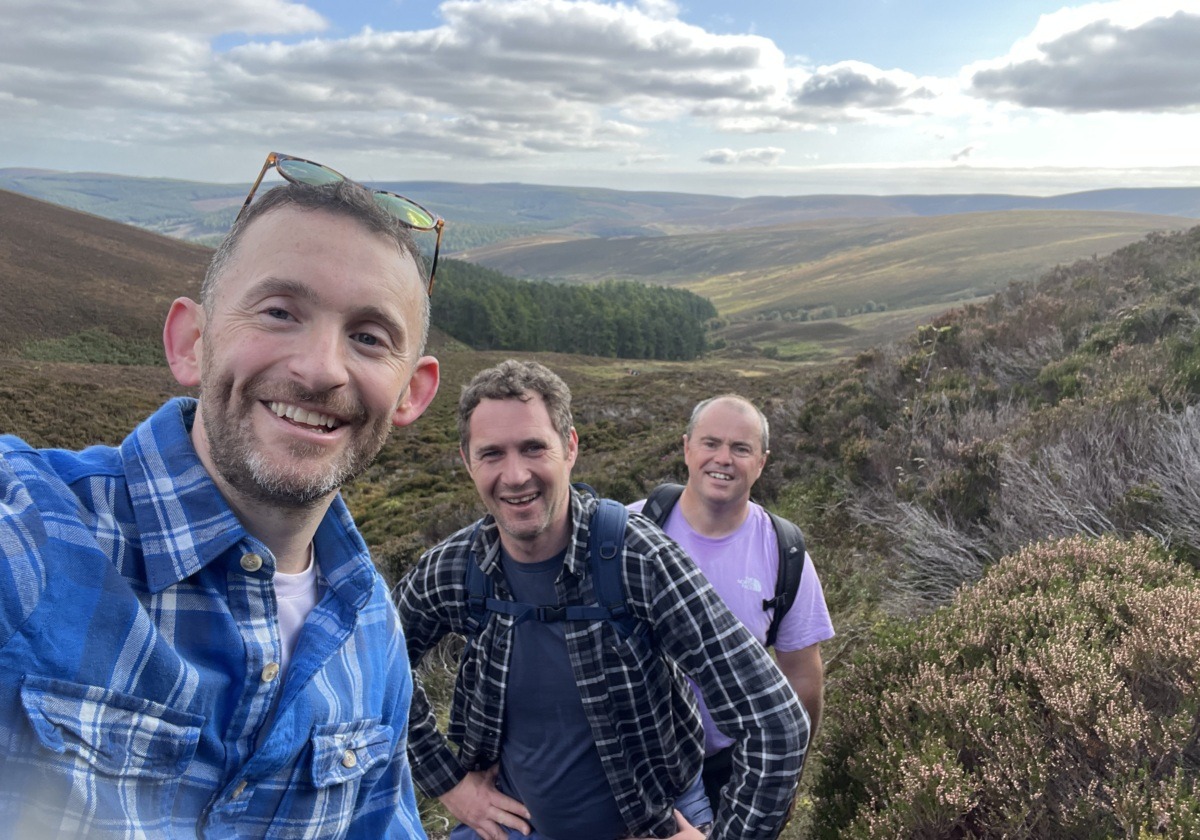 Three men hiking in the bush and smiling.