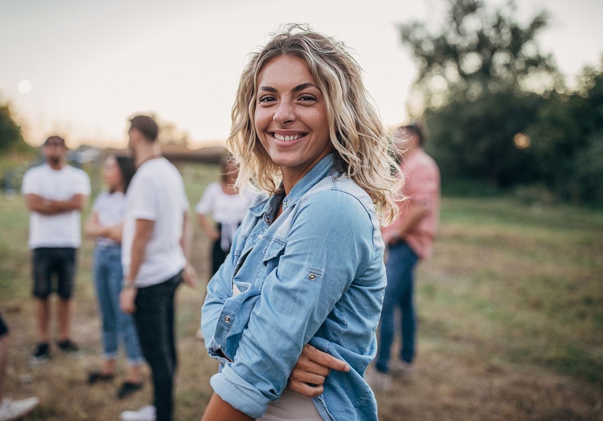 A smiling woman standing outside at dusk.